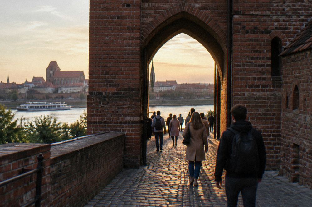Visitors walking through a brick gateway in Toruń's medieval city walls