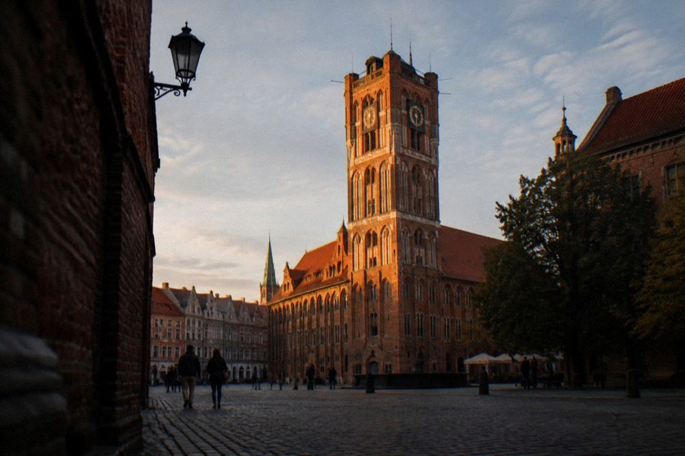 The illuminated tower of the Old Town Hall seen from a dark medieval square