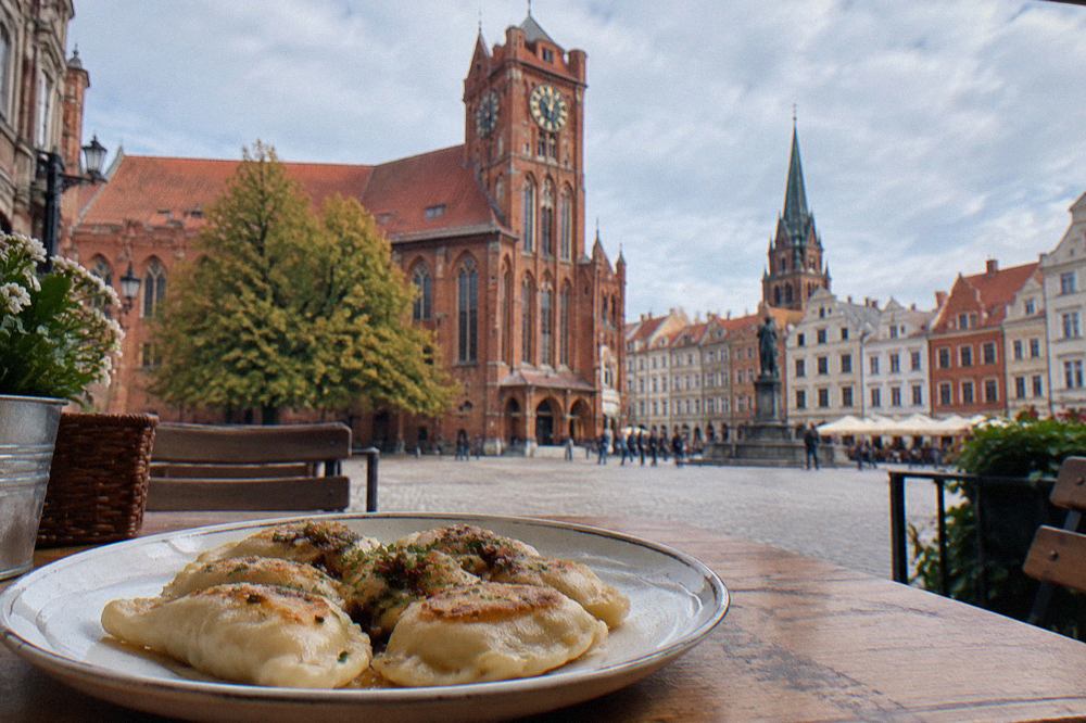 A plate of golden pierogi dumplings served on a wooden table in an Old Town restaurant