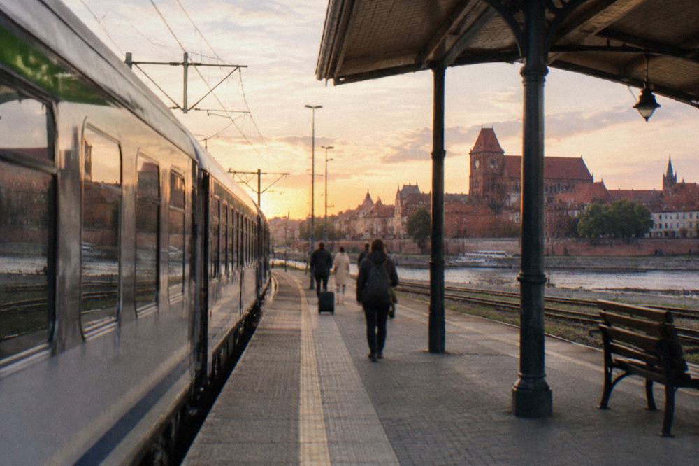 A passenger train standing at a platform beside a Polish railway station