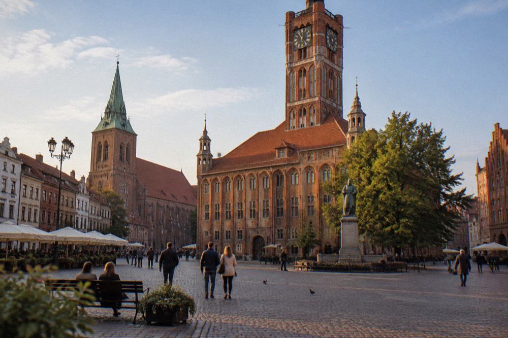 Medieval brick buildings of the Toruń Old Town seen from a cobbled square on a bright day