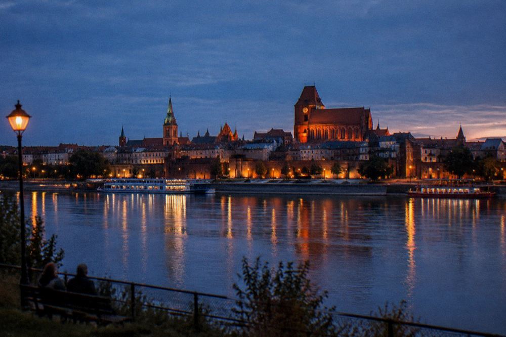 The Vistula river and the skyline of Toruń's Old Town seen from the far bank at dusk