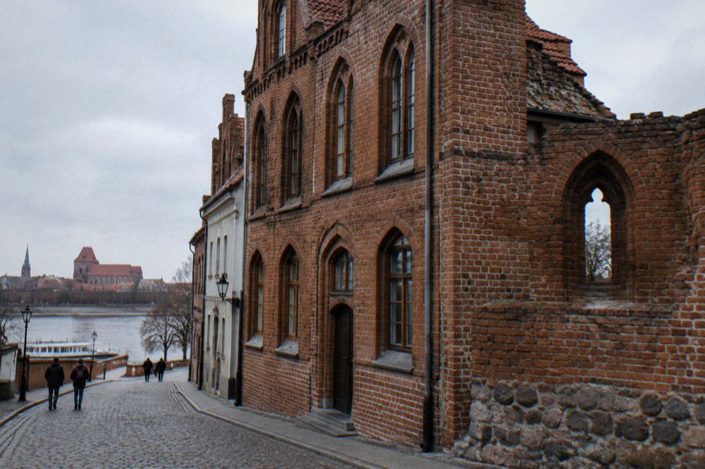 A brick Gothic townhouse on a narrow old town street in Toruń
