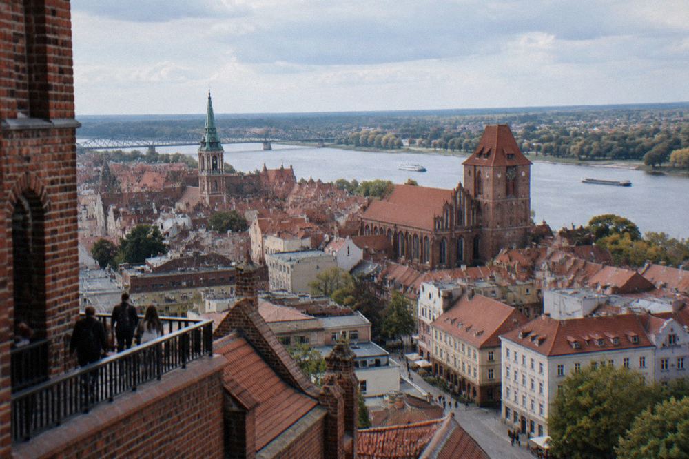 View from a high tower over red rooftops and church spires of Toruń's old town