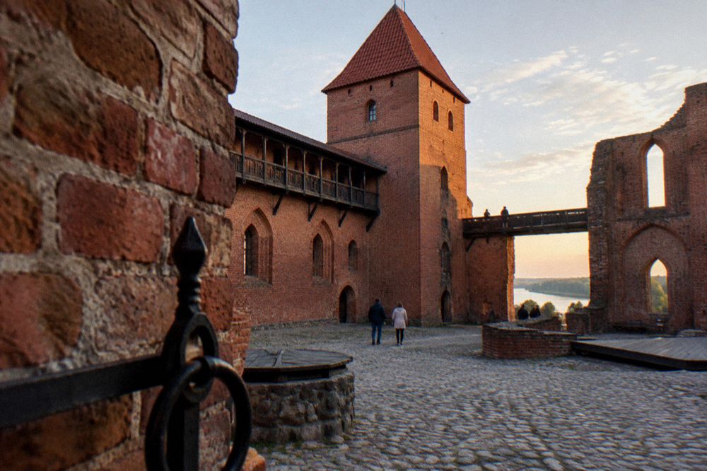 Red brick ruins of a medieval castle courtyard under an open sky