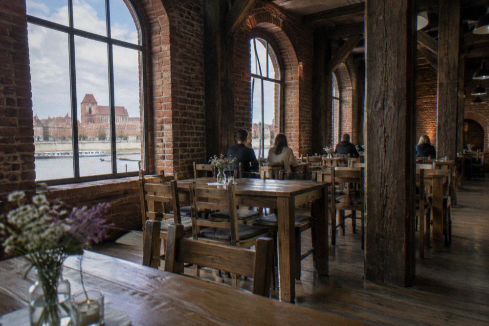 A dining room with wooden tables inside a historic Toruń granary building