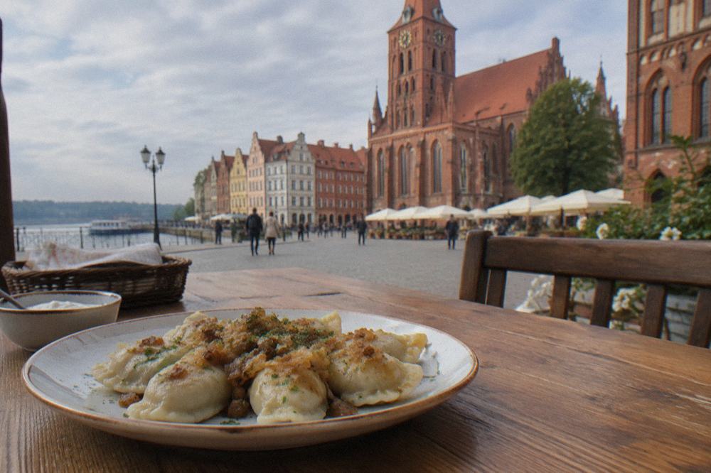 A plate of pierogi served on a wooden table in a Toruń restaurant