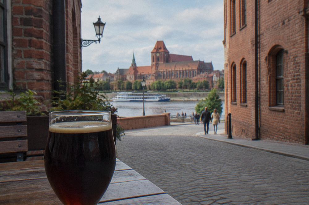 A glass of dark gingerbread beer on a brewery table in Toruń
