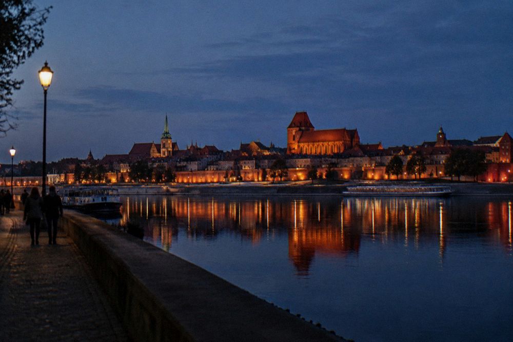 Evening lights of Torun Old Town towers reflected in the calm water of the Vistula river