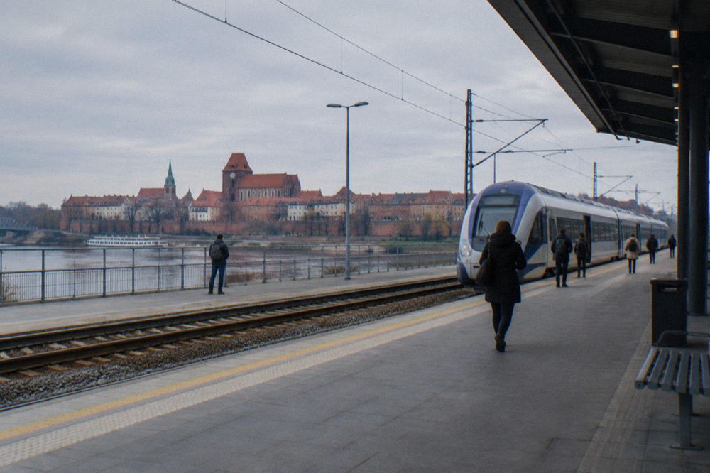 A modern railway platform with a passenger train waiting beside the track