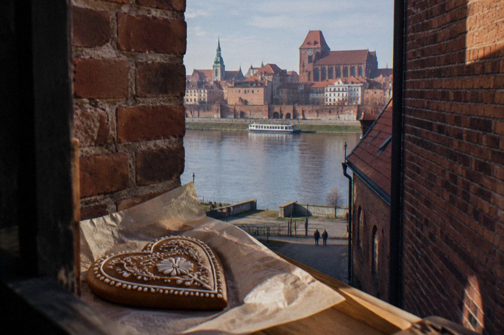 A hand-decorated gingerbread heart with white icing patterns resting on parchment paper