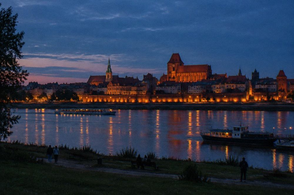 Evening view over Toruń Old Town rooftops with the Vistula river in the background