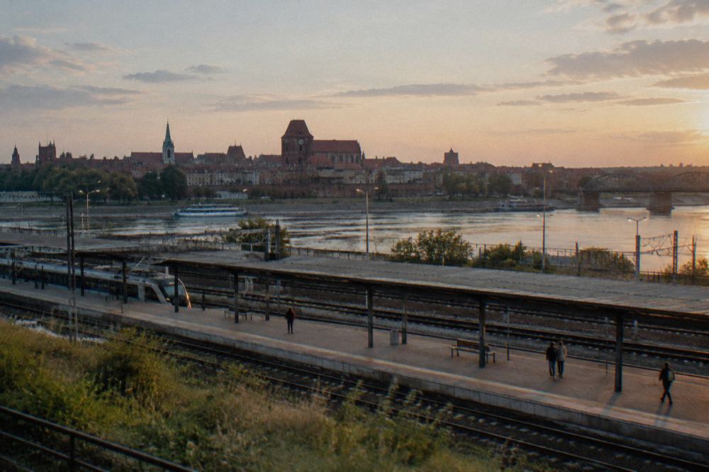 Railway platform at a Toruń train station with the city skyline beyond