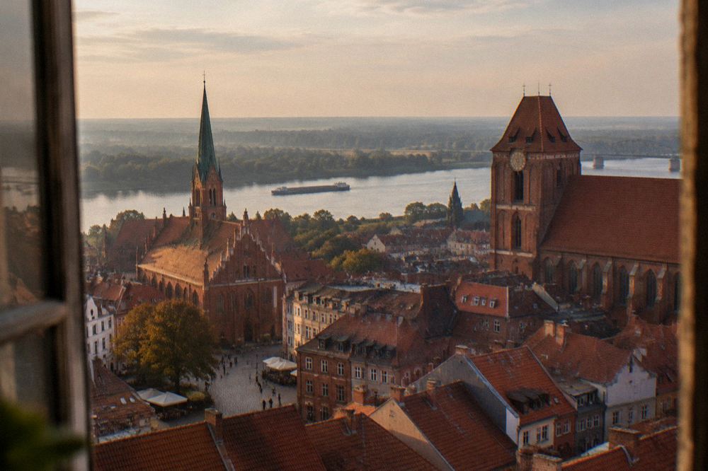 Aerial view of Toruń Old Town rooftops, church spires and the Vistula river beyond
