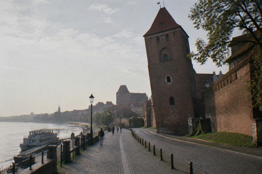 The leaning medieval tower beside a stretch of brick town wall in Torun