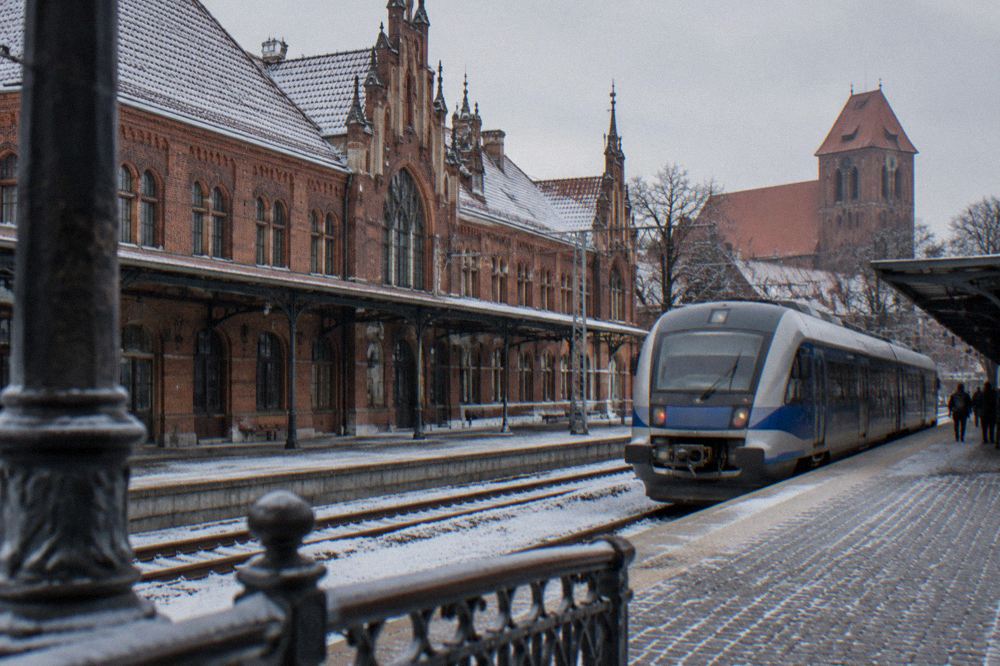 A regional train standing at a platform in winter with light snow on the tracks
