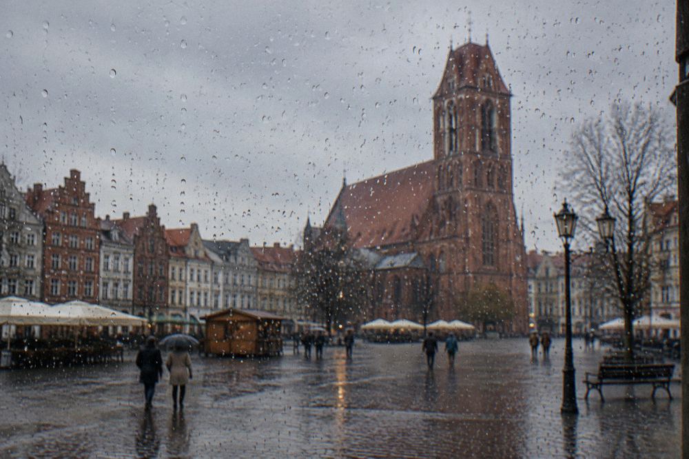 Raindrops on a window with the blurred outline of a brick Gothic church tower beyond the glass