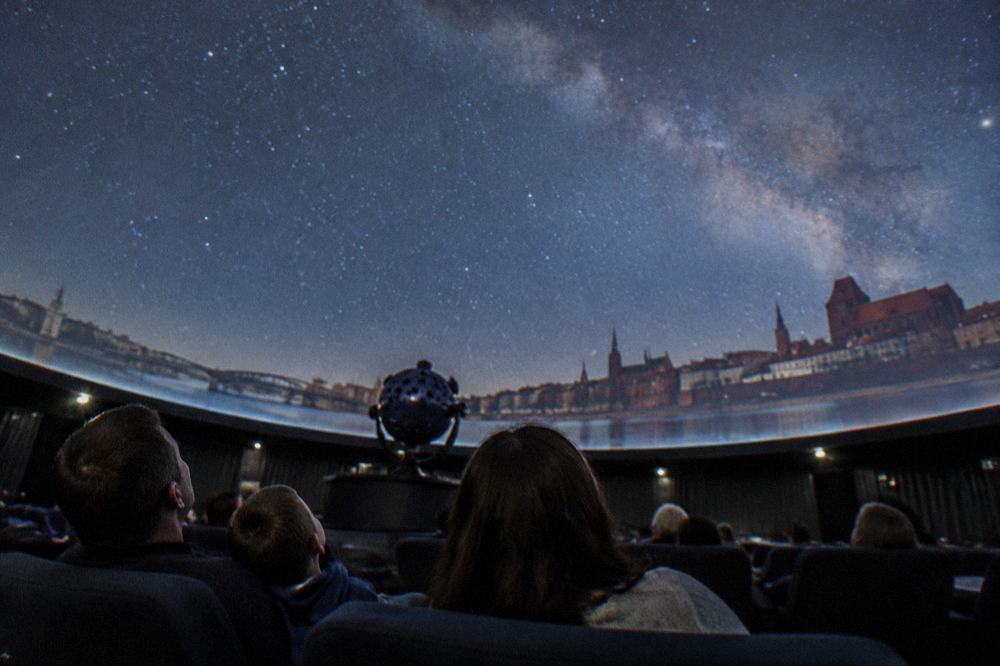 A family looking up at the domed ceiling of a planetarium show