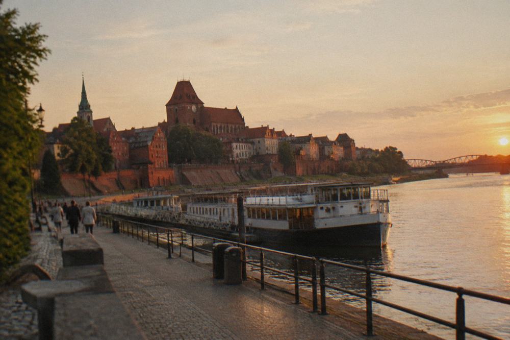 Riverside promenade along the Vistula below the brick town walls of Toruń at golden hour
