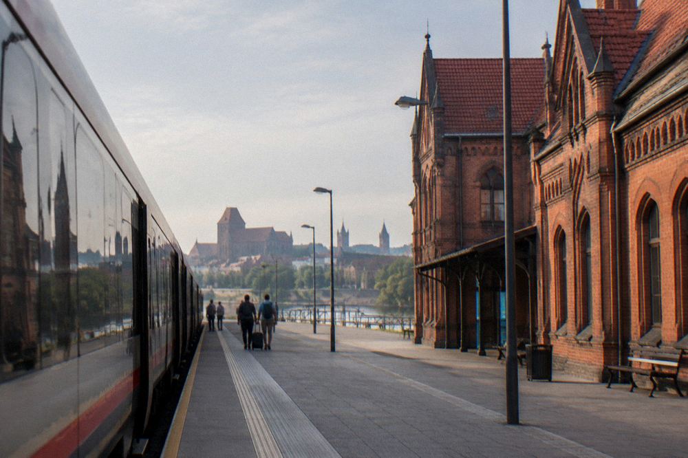 Train standing at a platform of a brick railway station in northern Poland on a bright morning